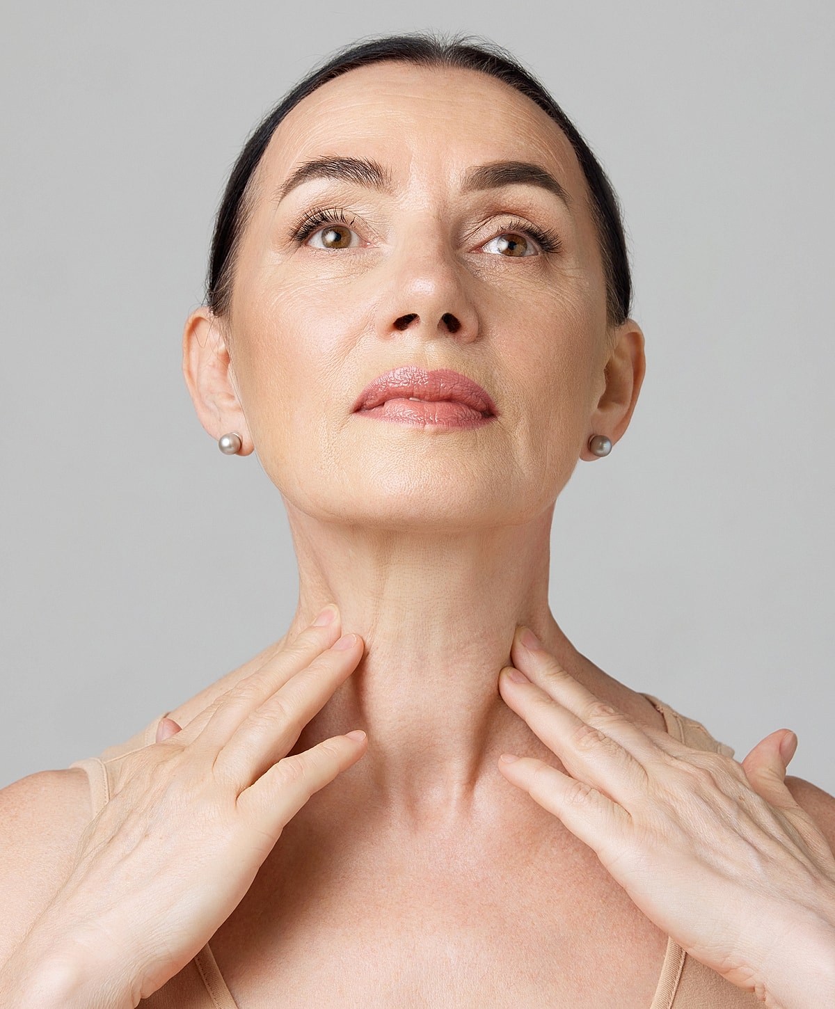 Woman gently touching her neck and jawline.