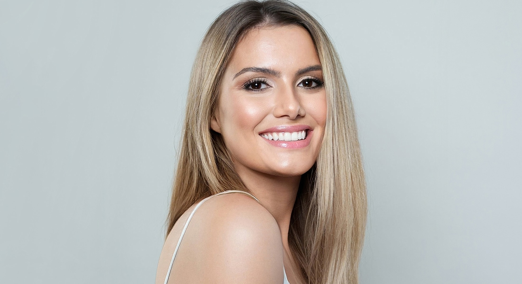 Smiling woman with long hair against light background.
