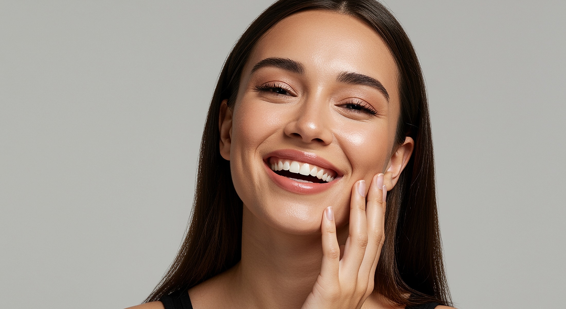 Smiling woman with glowing skin and long hair.